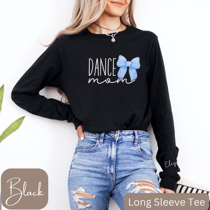 Może przedstawiać: Czarny T-shirt z długim rękawem z napisem "Dance Mom" i grafiką niebieskiej kokardki.