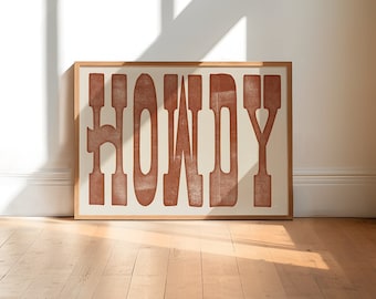 May include: A framed print with the word "HOWDY" in a rusty orange color on a white background.
