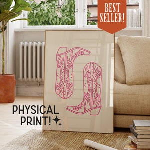 May include: A beige poster with a pink outline of two cowboy boots. The text "BEST SELLER!" is in a red box at the top of the poster. The text "PHYSICAL PRINT!" is at the bottom of the poster.