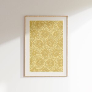 May include: A framed print with a yellow background and a white floral pattern. The pattern features stylised leaves and flowers.