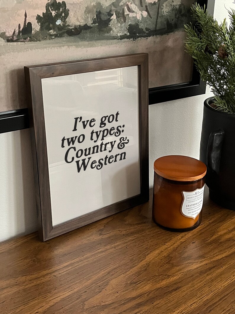 May include: A framed print with the text "I've got two types: Country & Western" in black lettering on a white background. The frame is dark brown wood.