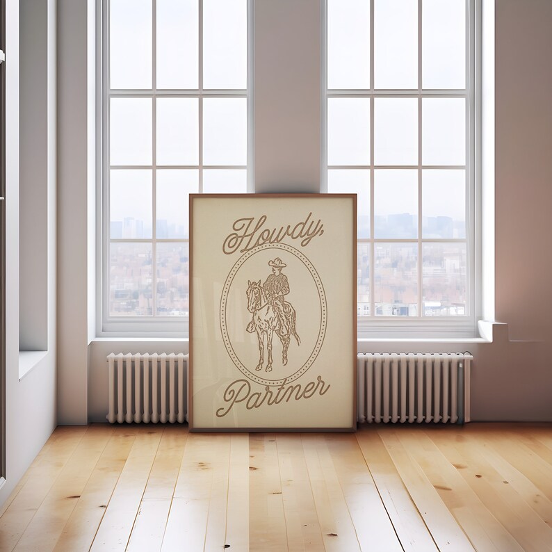 May include: A framed print with a beige background featuring a line drawing of a cowboy riding a horse. The text "Howdy Partner" is written in a stylized font.