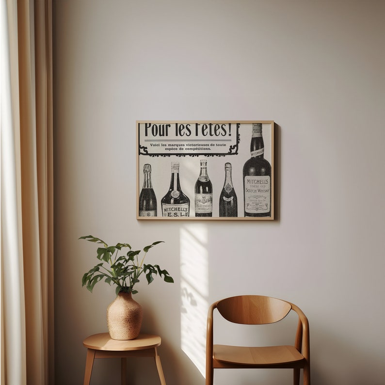 May include: A black and white vintage advertisement for a liquor brand. The ad features a framed poster with the text "Pour les f&ecirc;tes!" and images of various bottles of liquor. The poster is hanging on a light beige wall.