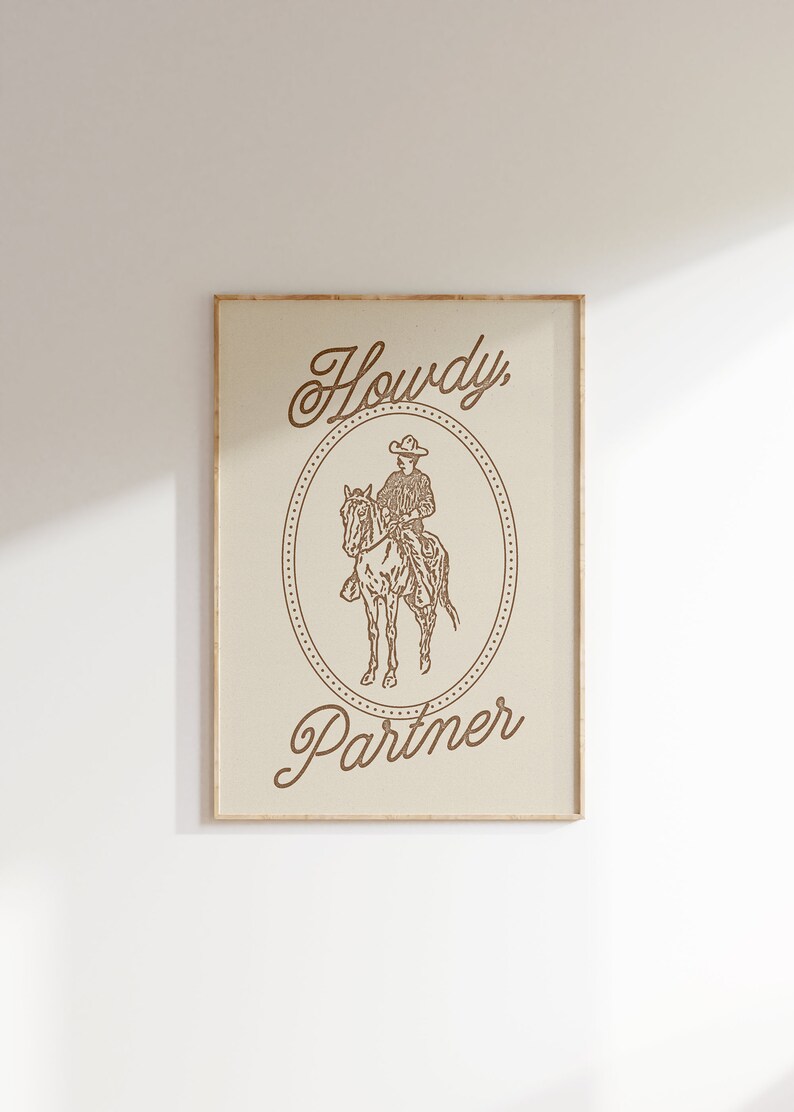 May include: A framed print with a cowboy riding a horse in a circle with the text "Howdy, Partner" in a cursive font.