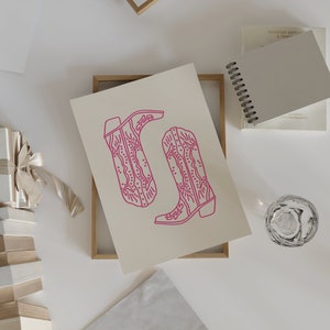 May include: A printable art print featuring a pair of pink cowboy boots with intricate designs. The boots are outlined in a bold pink color against a white background.