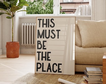 May include: A framed print with the text "This Must Be The Place" in black lettering on a white background.