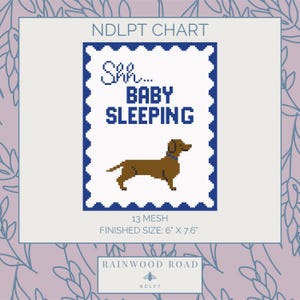 May include: A cross-stitch chart with a blue border and the text "Shh... BABY SLEEPING." A brown dachshund dog is below the text. The finished size is 15.2 cm x 19.3 cm. The chart also includes the text "13 MESH" and "RAINWOOD ROAD."
