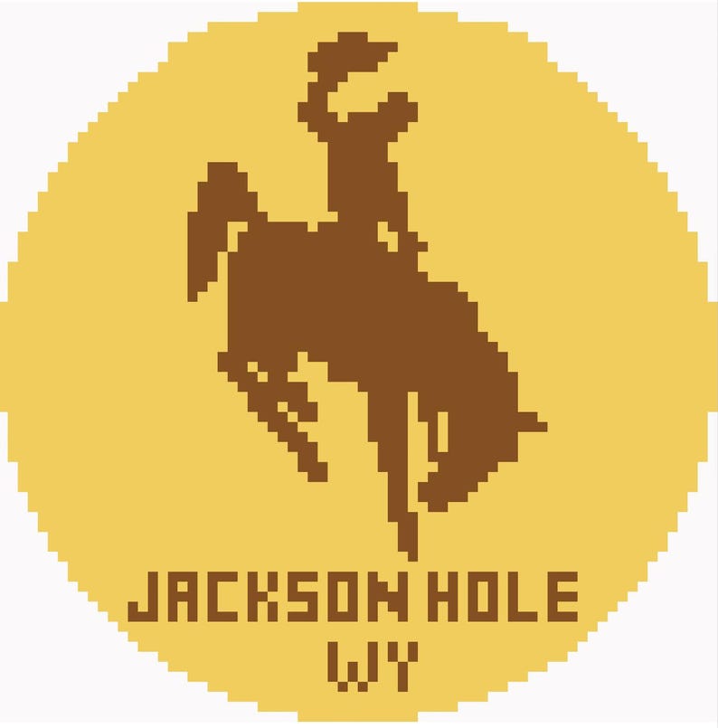 May include: A pixelated design featuring a brown silhouette of a cowboy riding a bucking bronco against a yellow background. The text "JACKSON HOLE WY" is displayed in a blocky font below the image.