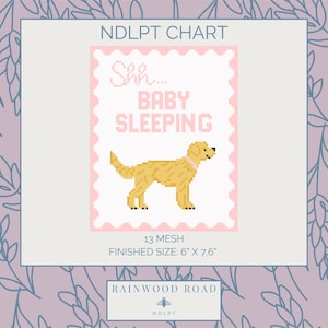May include: A cross-stitch pattern with a pink border and a light beige dog illustration. The text reads "Shh... BABY SLEEPING". Finished size is 15.2 cm x 19.3 cm. The bottom of the image has the text "RAINWOOD ROAD".
