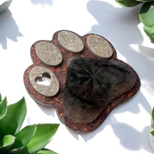 May include: A brown resin paw print with a heart-shaped cutout and a clear resin centre with a glittery design.