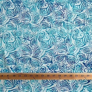 May include: White fabric with a blue and teal paisley pattern. The fabric is measured with a ruler in inches.