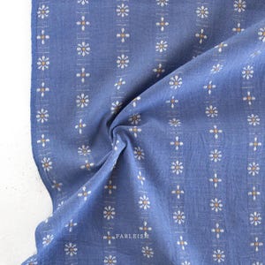 May include: Blue cotton fabric with a white and gold floral pattern. The fabric is folded and shows the pattern repeating.