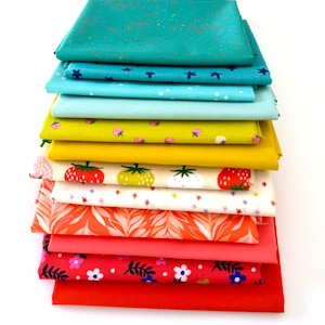 May include: A stack of colorful fabric squares in various shades of teal, blue, yellow, orange, pink, and red. Some fabrics feature patterns of strawberries, flowers, and abstract designs. The fabrics are neatly folded and stacked.