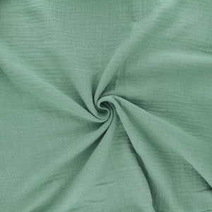 May include: A soft, light green fabric with a crinkled texture. The fabric is folded and draped, showing its texture and drape.