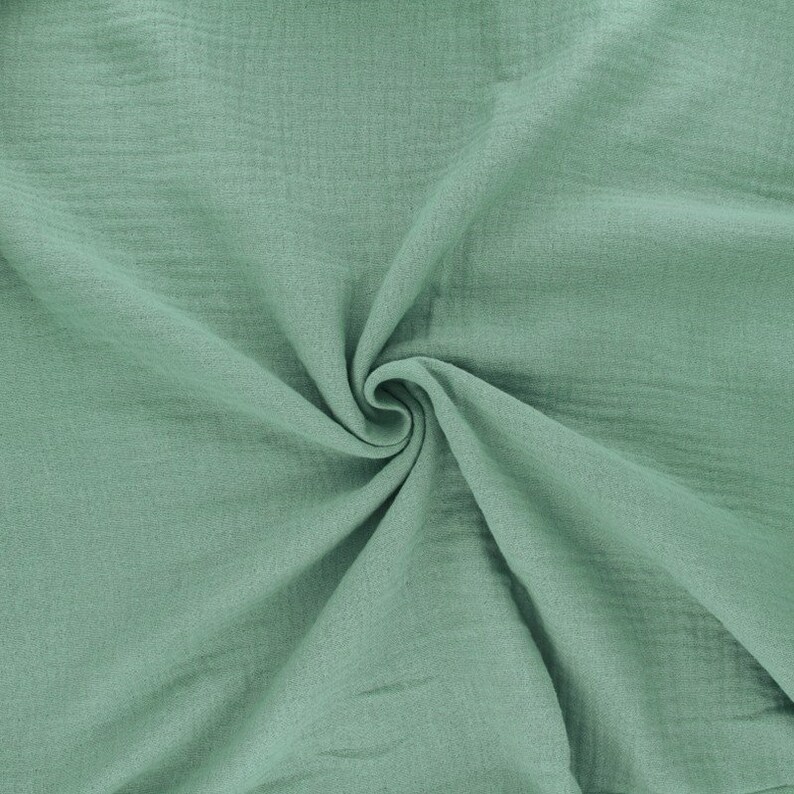 May include: A soft, light green fabric with a crinkled texture. The fabric is folded and draped, showing its texture and drape.