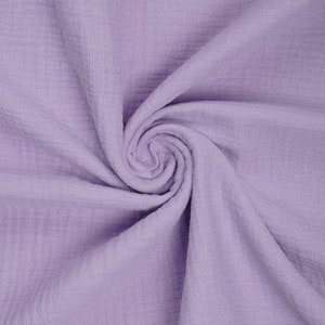May include: A close-up of a soft, light purple fabric with a crinkled texture. The fabric is folded and draped, showing its texture and drape.