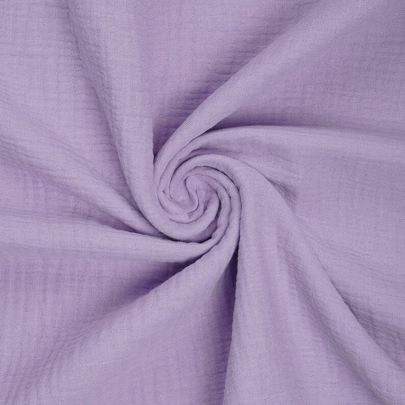 May include: A close-up of a soft, light purple fabric with a crinkled texture. The fabric is folded and draped, showing its texture and drape.