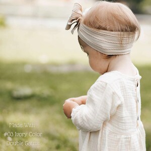 May include: A young child wearing a white dress with a bow headband. The dress is made of double gauze fabric and is ivory in color. The text "Made With #03 Ivory Color Double Gauze" is visible at the bottom of the image.