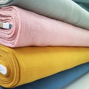 May include: Four rolls of fabric in different colors: light blue, pink, yellow, and blue. The fabric is a soft, textured material.