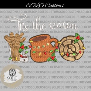 May include: Embroidered design featuring a mug of hot chocolate, a cinnamon roll, and a bundle of cinnamon sticks. The text "Tis the season" is embroidered in white above the design.