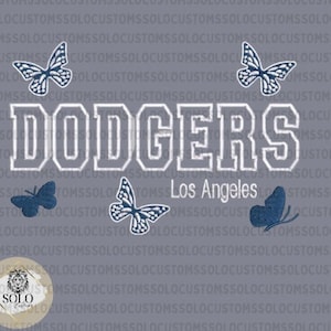 May include: A gray t-shirt with a white embroidered "Dodgers" logo and the words "Los Angeles" below. The shirt features four blue butterfly designs.