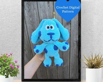 Könnte beinhalten: Gerahmtes Bild eines hellblauen Häkelhundes mit dunkelblauen Flecken. Der Hund hat große Schlappohren und einen freundlichen Ausdruck. Eine blaue herzförmige Grafik mit dem Text "Crochet Digital Pattern" befindet sich oben rechts.