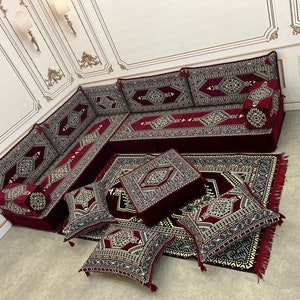May include: A burgundy and cream patterned floor seating set with a large couch, multiple cushions, and a matching rug. The set is arranged in a living room setting.