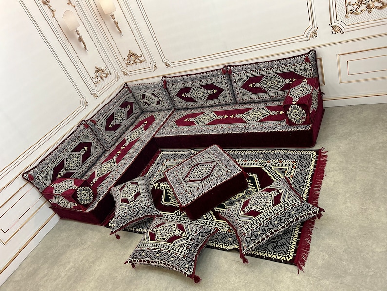 May include: A burgundy and cream patterned floor seating set with a large couch, multiple cushions, and a matching rug. The set is arranged in a living room setting.
