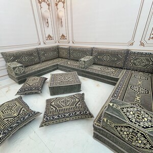 May include: A gray and black patterned L-shaped sectional sofa with multiple cushions. The sofa is made of fabric and has a traditional design.