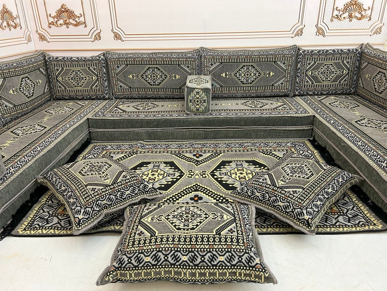 May include: A gray and black patterned floor cushion with a geometric design. The cushion is part of a larger set of cushions and a sofa, all with the same pattern.