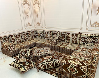 May include: A brown and beige patterned sectional sofa with multiple cushions and pillows. The sofa is arranged in a U-shape and is made of a soft, plush fabric.
