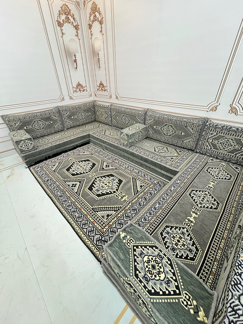 May include: A gray and black patterned floor cushion set with a matching rug. The cushions are arranged in a U-shape and are perfect for lounging. The rug has a geometric design and is made of a soft, plush material.