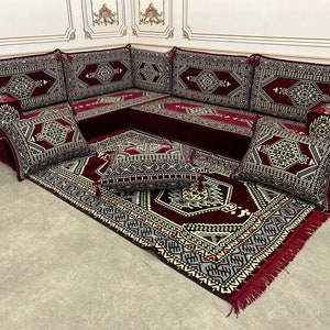 May include: A burgundy and cream patterned sectional sofa with multiple cushions and a matching rug. The sofa is made up of individual pieces that can be arranged in different configurations.