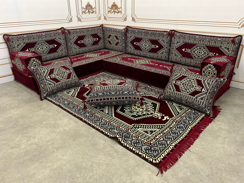 May include: A burgundy and cream patterned sectional sofa with multiple cushions and a matching rug. The sofa is made up of individual pieces that can be arranged in different configurations.