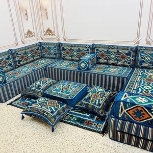 Peut inclure: Un grand canapé d'angle avec un motif géométrique bleu et blanc. Le canapé comprend plusieurs coussins et oreillers avec un design assorti. Le style général est un design traditionnel à motifs.