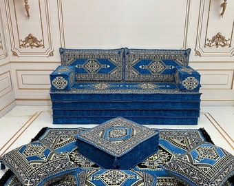 May include: A blue and gold patterned floor cushion set with a matching sofa. The set includes four square cushions and one rectangular cushion. The cushions are all decorated with intricate geometric patterns.