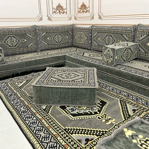 May include: A gray and white patterned floor cushion set with a matching rug. The cushions are arranged in a U-shape and feature intricate geometric designs. The rug has a similar pattern and is made of a soft, plush material.