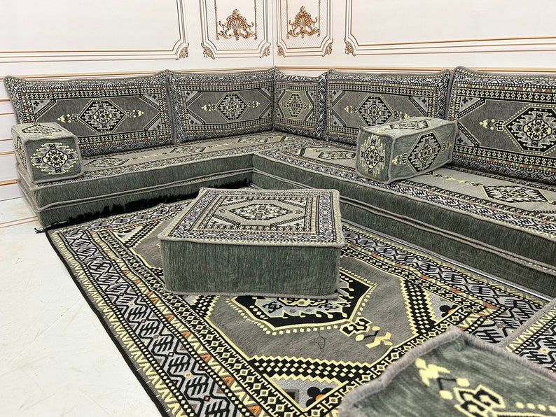 May include: A gray and white patterned floor cushion set with a matching rug. The cushions are arranged in a U-shape and feature intricate geometric designs. The rug has a similar pattern and is made of a soft, plush material.