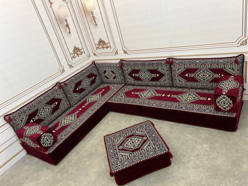 May include: A burgundy and gold patterned floor seating set with a matching ottoman. The set is made of plush fabric and features intricate geometric designs.