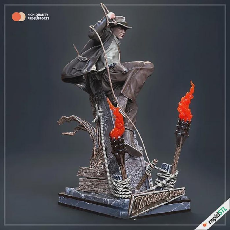 May include: A detailed statue of Indiana Jones in a dynamic pose, holding a whip and climbing. The figure is dressed in a brown hat, jacket, and pants. Two torches with orange flames flank the figure. The base features the text "INDIANA JONES".
