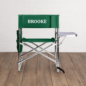 May include: A green folding chair with a side table and the name "BROOKE" printed on the back.