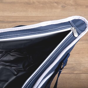 Puede incluir: Una bolsa de refrigeraci&oacute;n azul y blanca con cierre de cremallera. La bolsa est&aacute; abierta y el interior est&aacute; forrado con un material plateado.