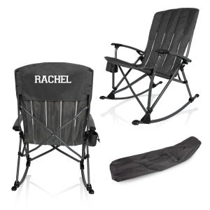 May include: A dark gray folding rocking chair with a black frame. The chair has a high back with vertical slats and armrests. The word "RACHEL" is printed in white on the back of the chair. A matching carrying case is also included.