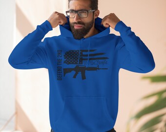 May include: A royal blue hoodie with a black graphic featuring an American flag design, a rifle, and the text "DEFEND THE 2ND" and "We The People". The hoodie has a hood and long sleeves.