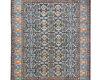 Puede incluir: Una alfombra persa tradicional con fondo azul oscuro y intrincados patrones florales en tonos naranja, azul y blanco. La alfombra tiene un borde con un patrón repetitivo de flores y hojas estilizadas.