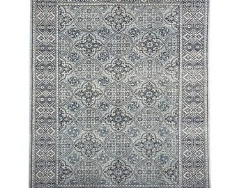 Puede incluir: Una alfombra azul y blanca con un diseño geométrico. La alfombra tiene un borde con un patrón repetitivo.