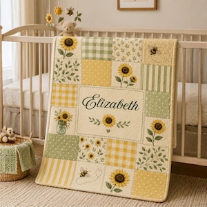 May include: A patchwork baby quilt with a sunflower and bee theme. The quilt features squares of yellow, green, and white patterns, including gingham, polka dots, and stripes. The name "Elizabeth" is embroidered in the center.
