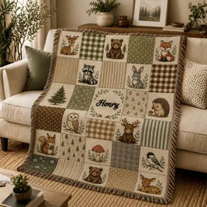 May include: A beige and green patchwork throw blanket featuring woodland animals and trees. The blanket has a fringed edge and includes the name "Henry" in the center. The squares feature a deer, bear, raccoon, rabbit, fox, owl, squirrel, moose, hedgehog, mushroom, and bird.
