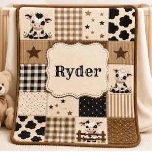 May include: A patchwork baby blanket featuring a variety of patterns in brown, tan, and black. The blanket includes images of cartoon cows and the name "Ryder" in a decorative font. The blanket is trimmed with a brown border.