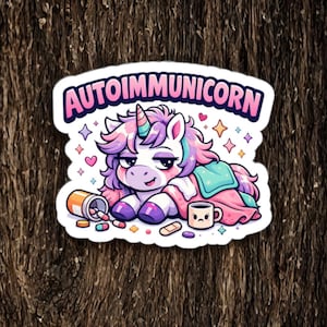 May include: A sticker featuring a cartoon unicorn with a rainbow mane and horn, lying down with a blanket and a mug. The text "AUTOIMMUNICORN" is above the unicorn. Pills and a bandage are next to the unicorn.